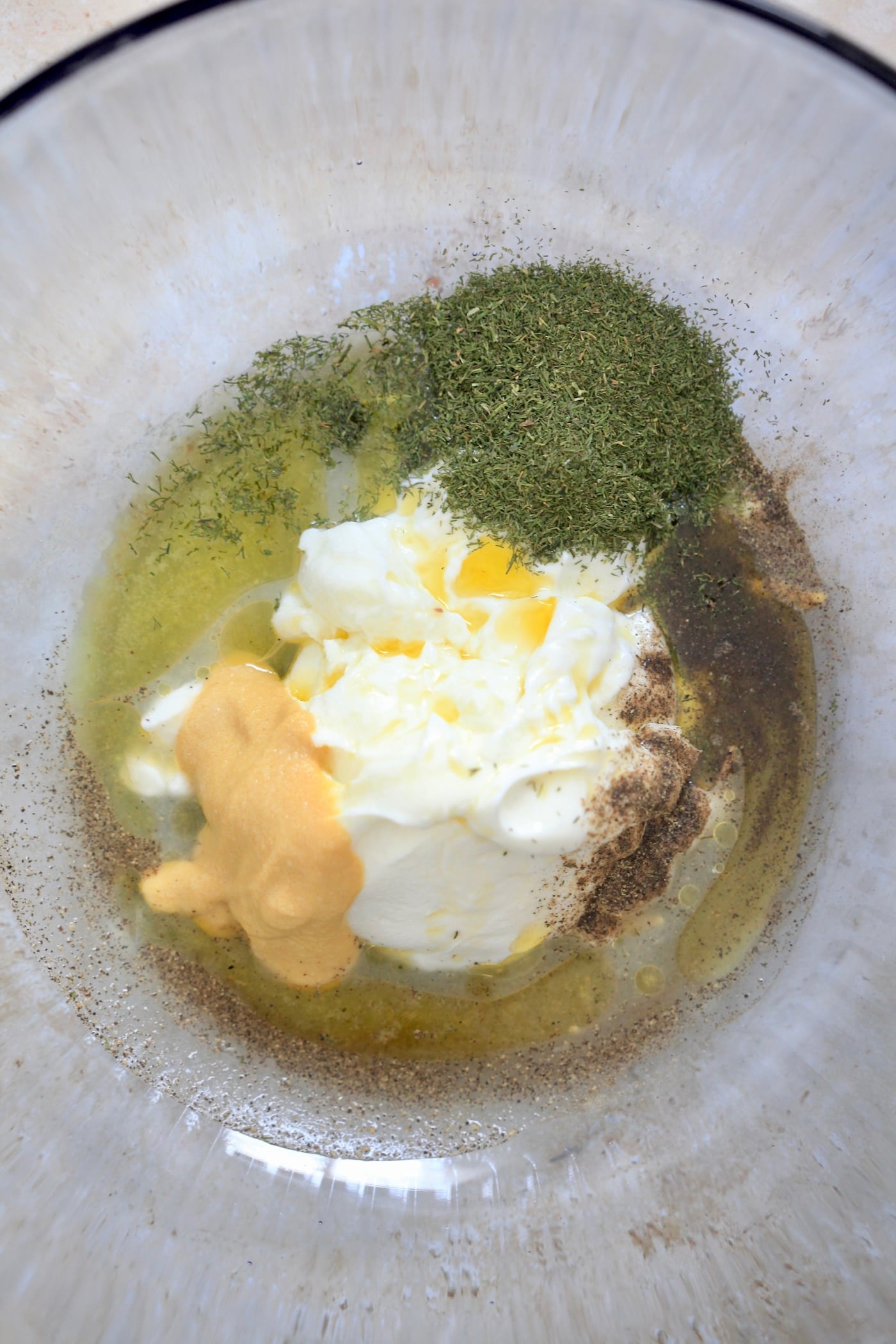yogurt, oil, lemon and dill in bowl.