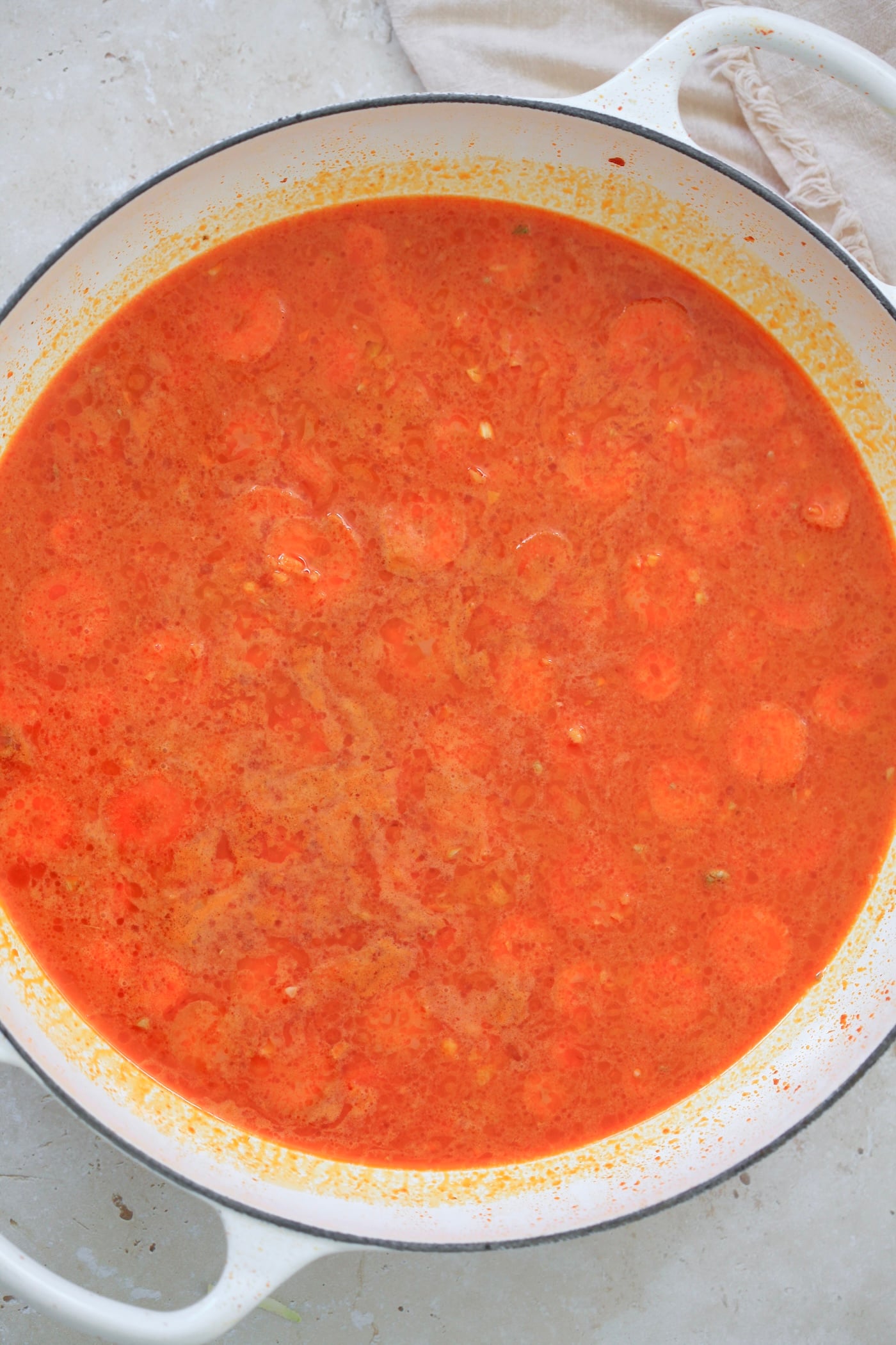 sliced carrots in red liquid in pan.
