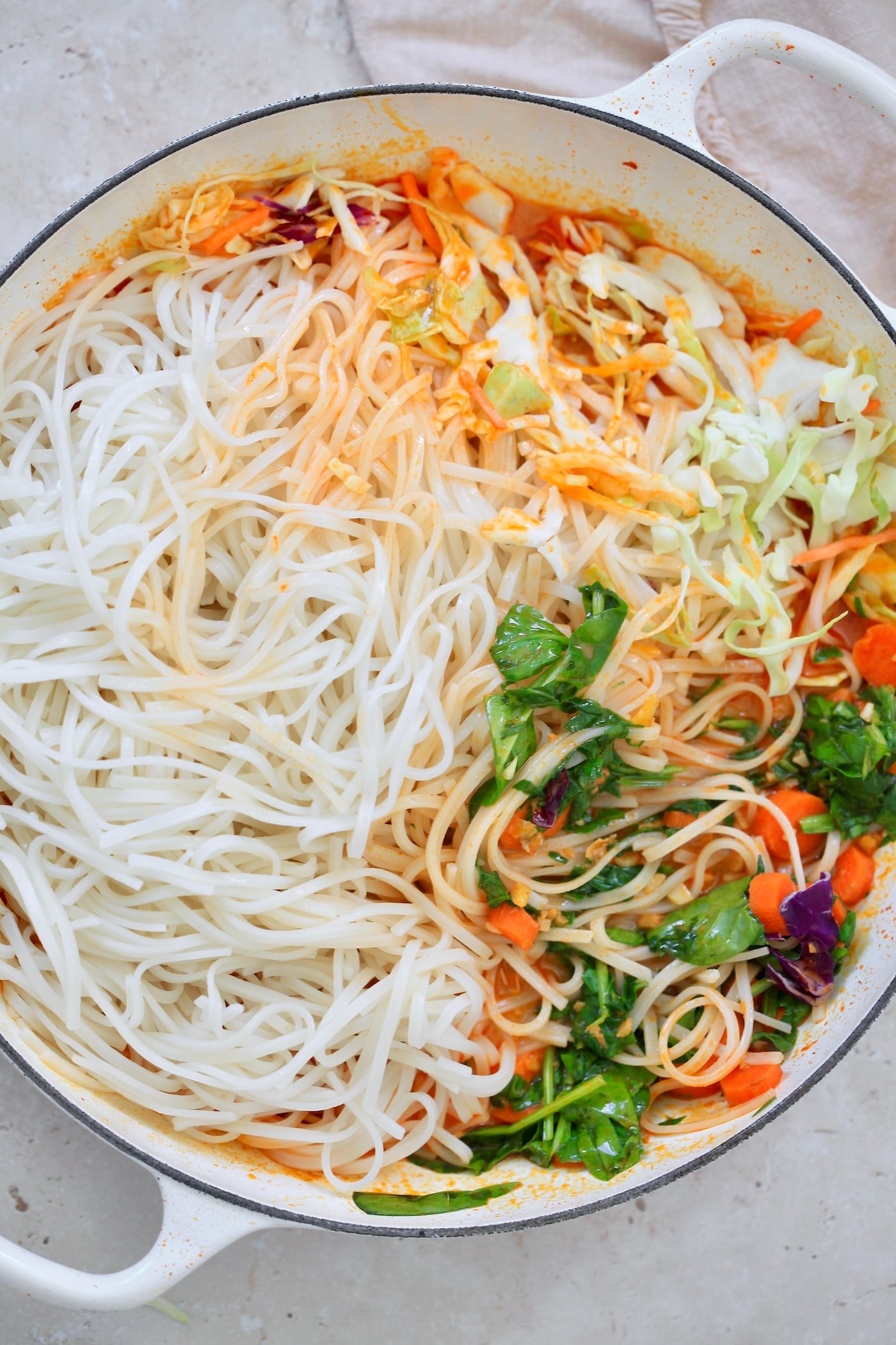 white noodles in pan next to veggies.