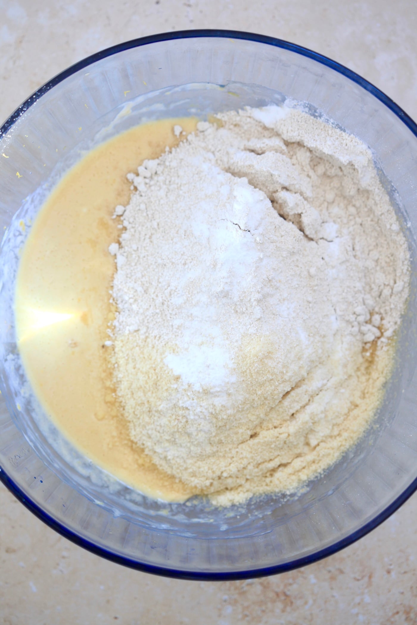 flour on top of yellow liquid in blue bowl.