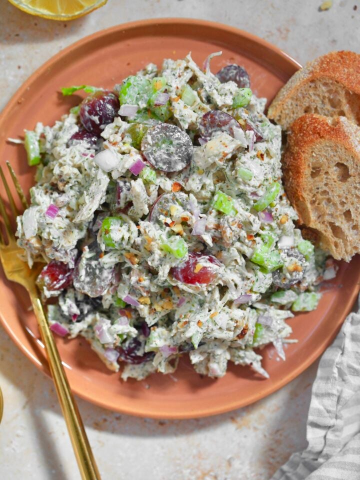 orange plate with colorful chicken salad on it with bread