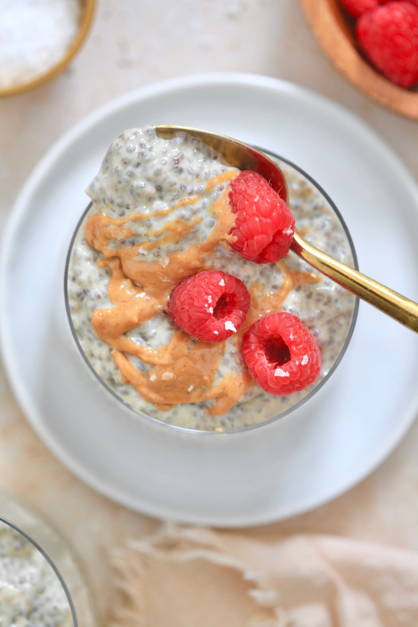 overhead view of glass with chia pudding with peanut butter drizzle and raspberries.