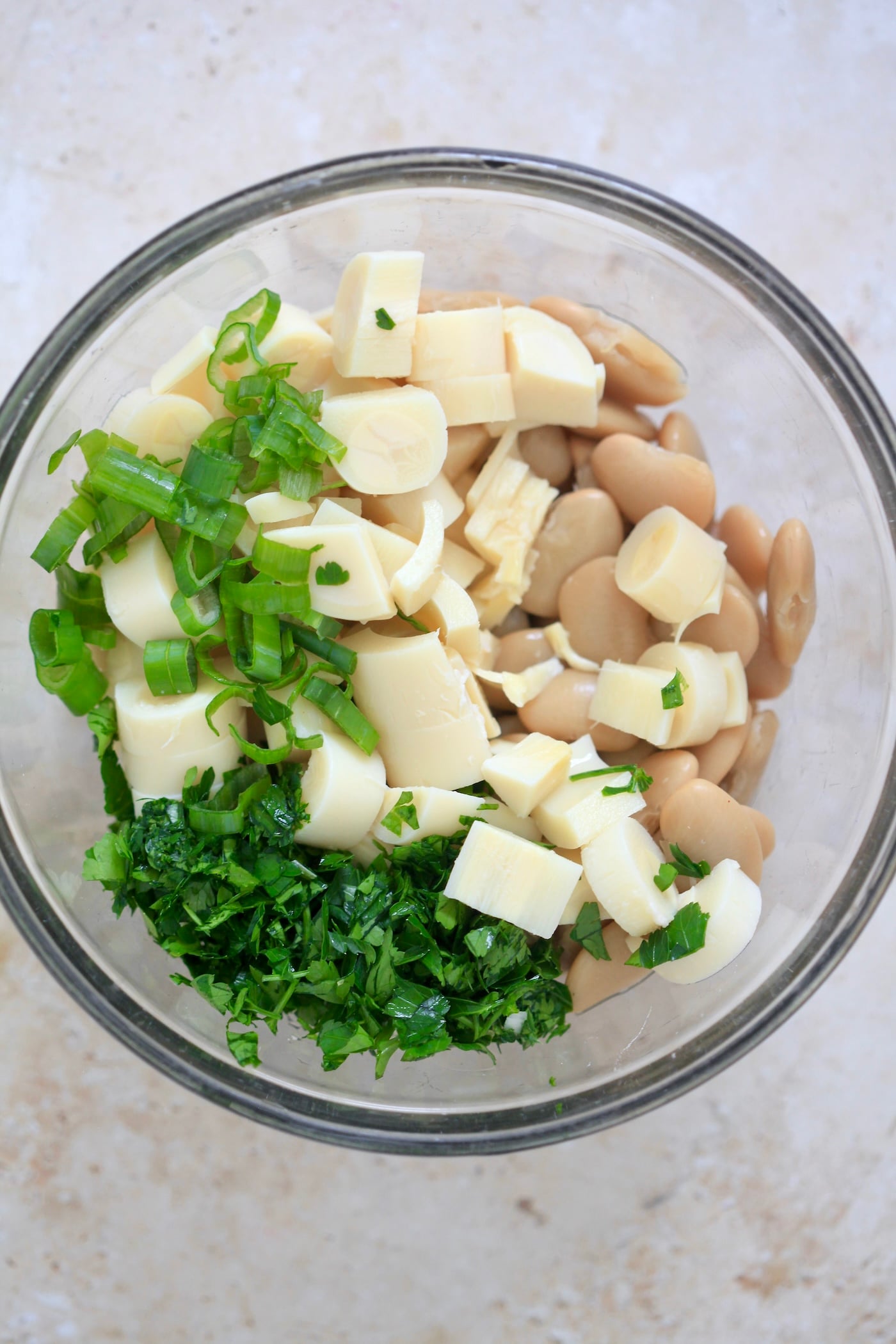 glass bowl with beans, hearts of pal, and herbs