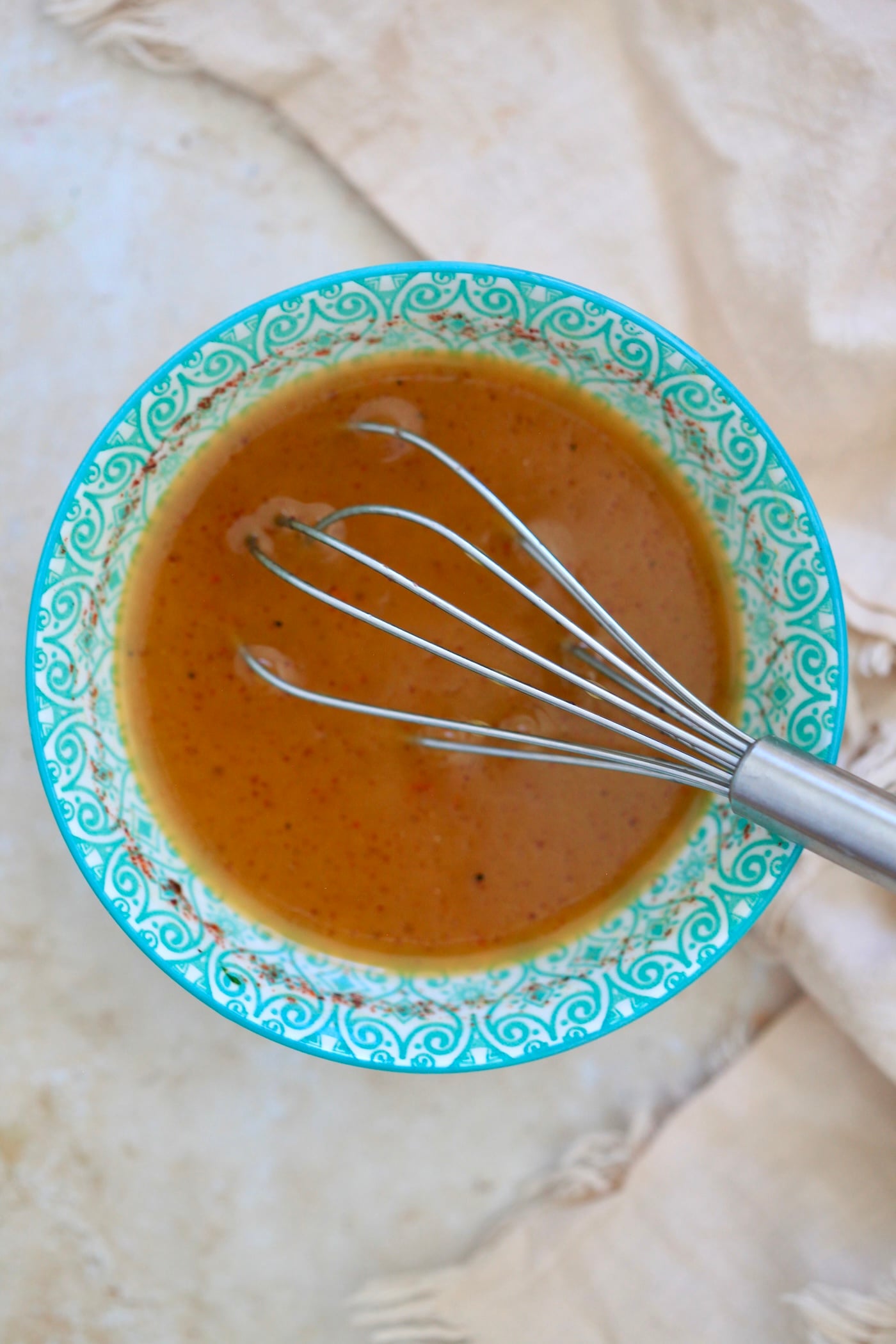 brown dressing in blue bowl with whisk.
