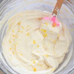 white frosting with lemon zest in glass bowl.