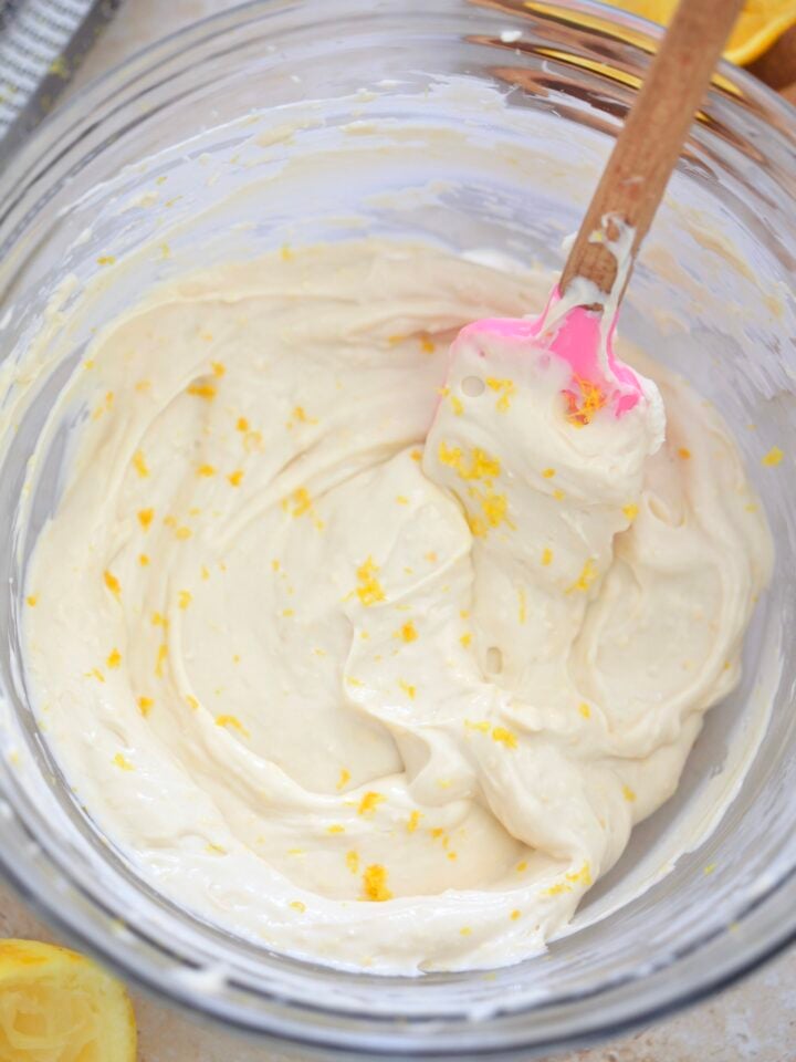 white frosting with lemon zest in glass bowl.