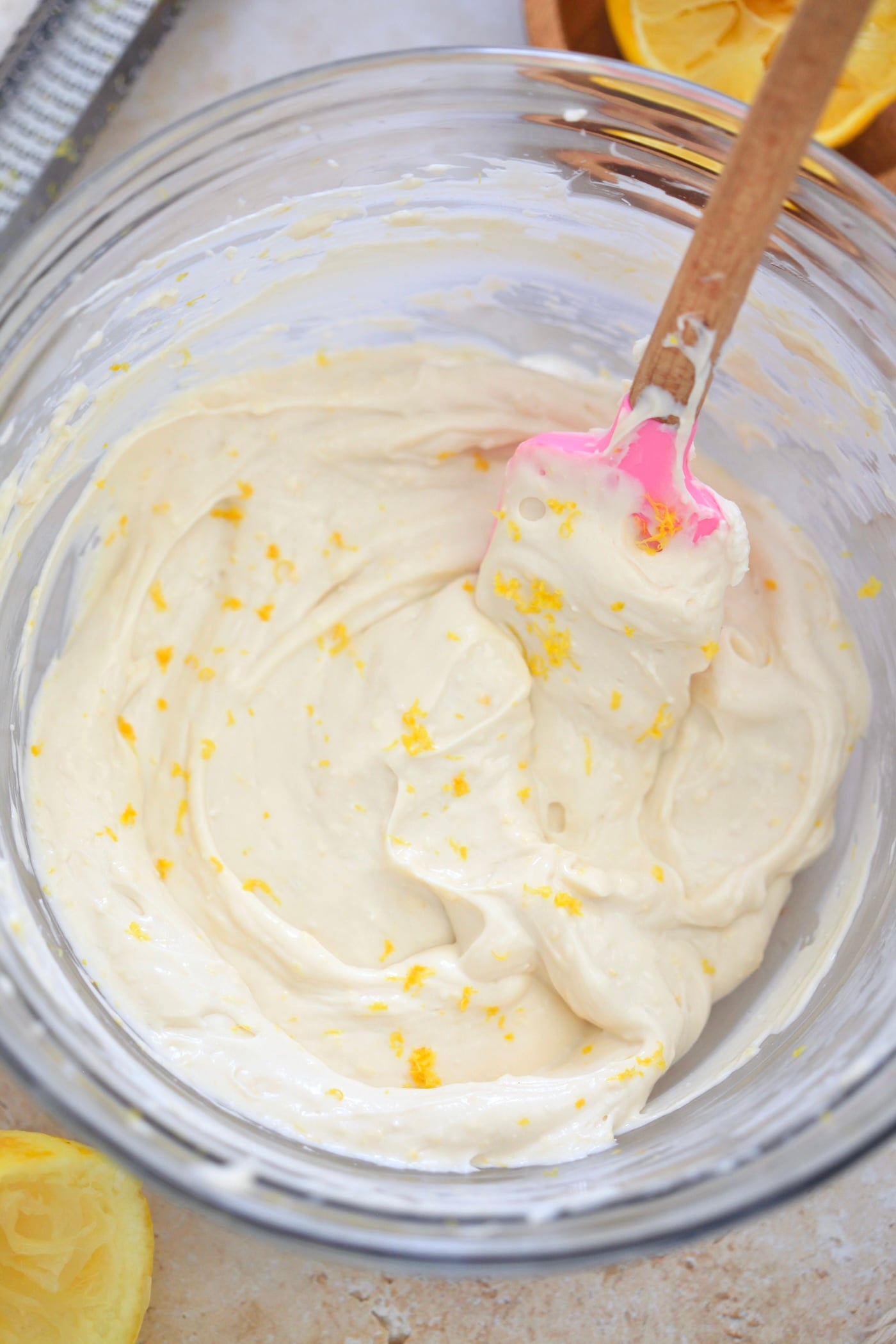 white frosting with lemon zest in glass bowl.