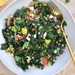 kale salad in white bowl with gold fork