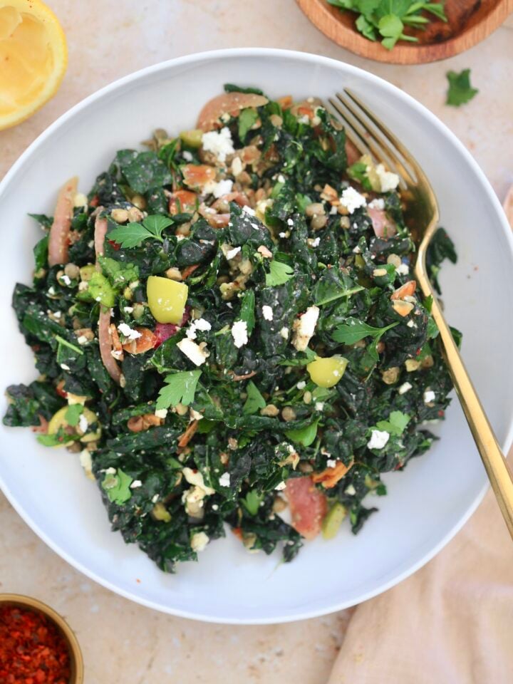 kale salad in white bowl with gold fork
