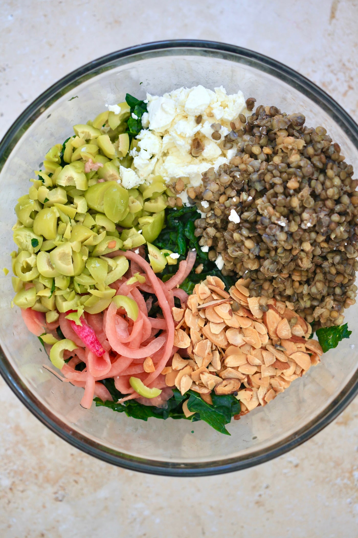 lentils, olives, onions, and feta in glass bowl.