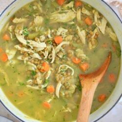 white pot with golden chunky soup and wooden spoon.
