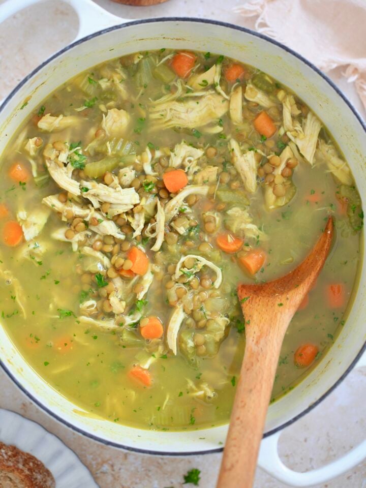 white pot with golden chunky soup and wooden spoon.
