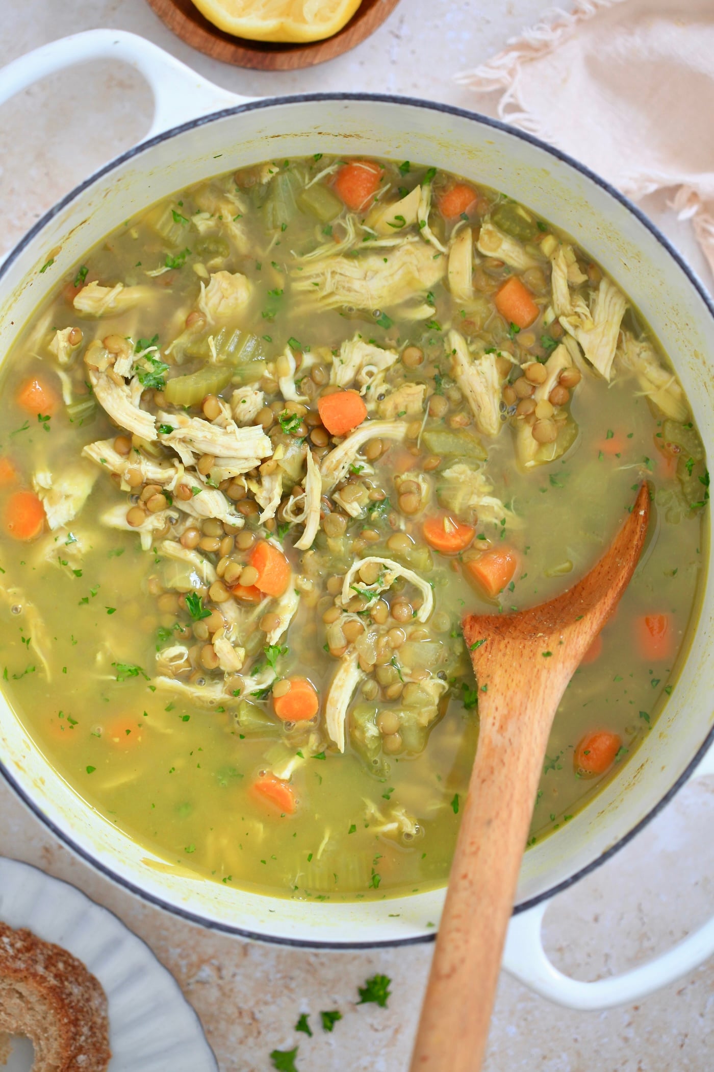 white pot with golden chunky soup and wooden spoon.