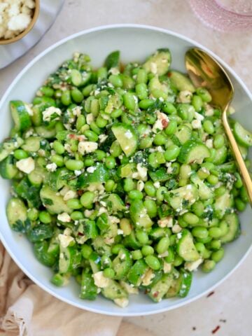 bowl with green edamame salad and gold spoon.
