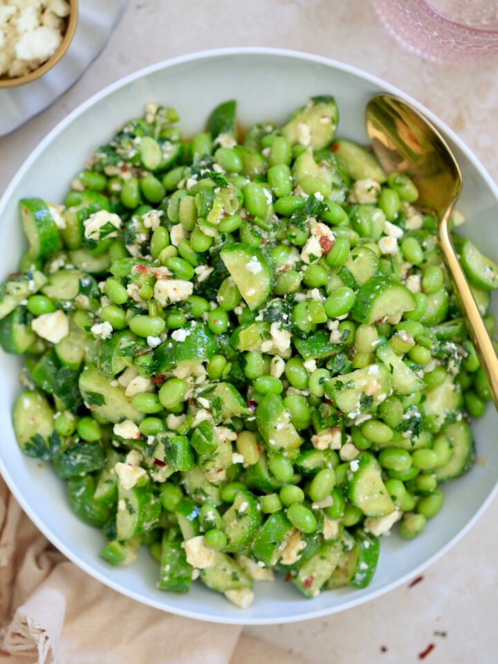 bowl with green edamame salad and gold spoon.
