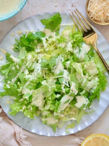 greens on plate with creamy pale dressing and lemon.
