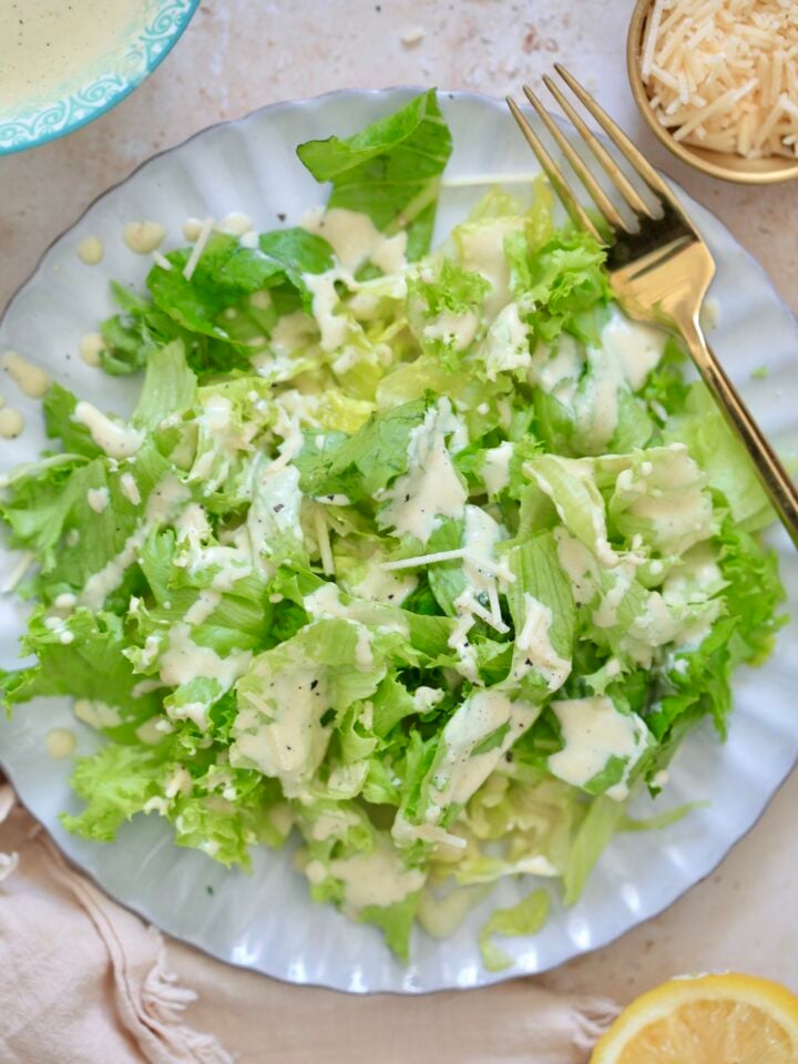 greens on plate with creamy pale dressing and lemon.
