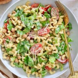 white bowl with creamy pasta salad with tomatoes and lettuce
