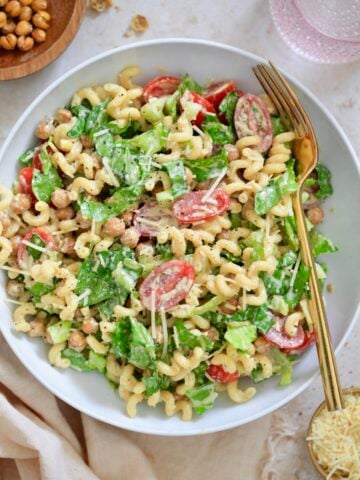 white bowl with creamy pasta salad with tomatoes and lettuce