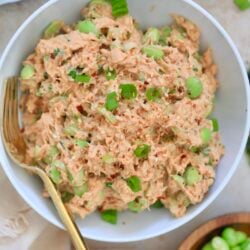 bowl with pink creamy tuna salad with green bits.