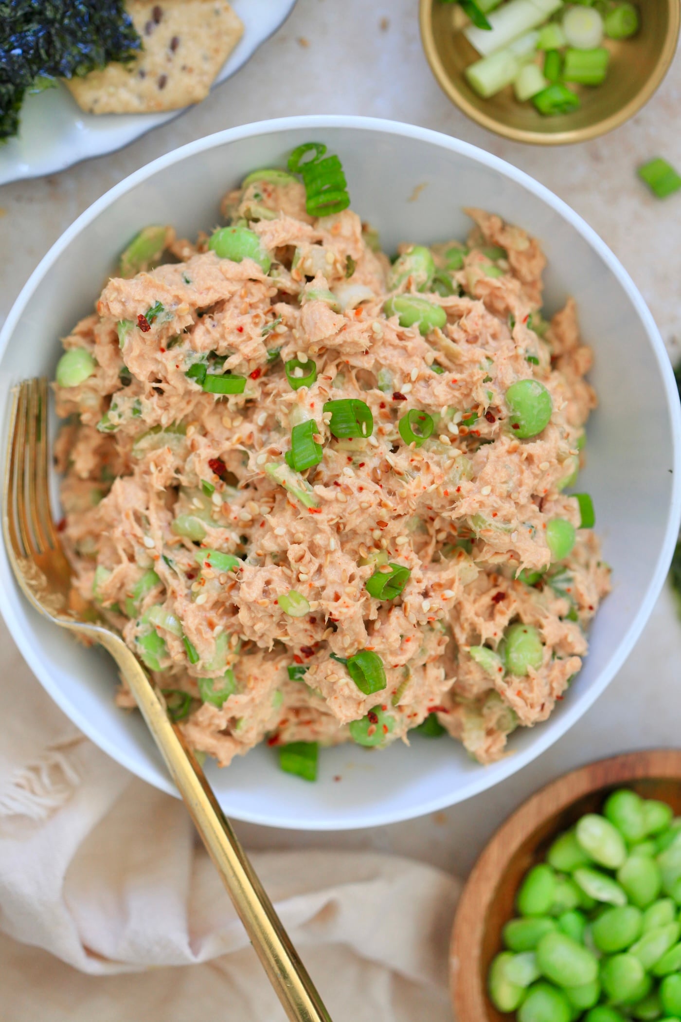 bowl with pink creamy tuna salad with green bits.