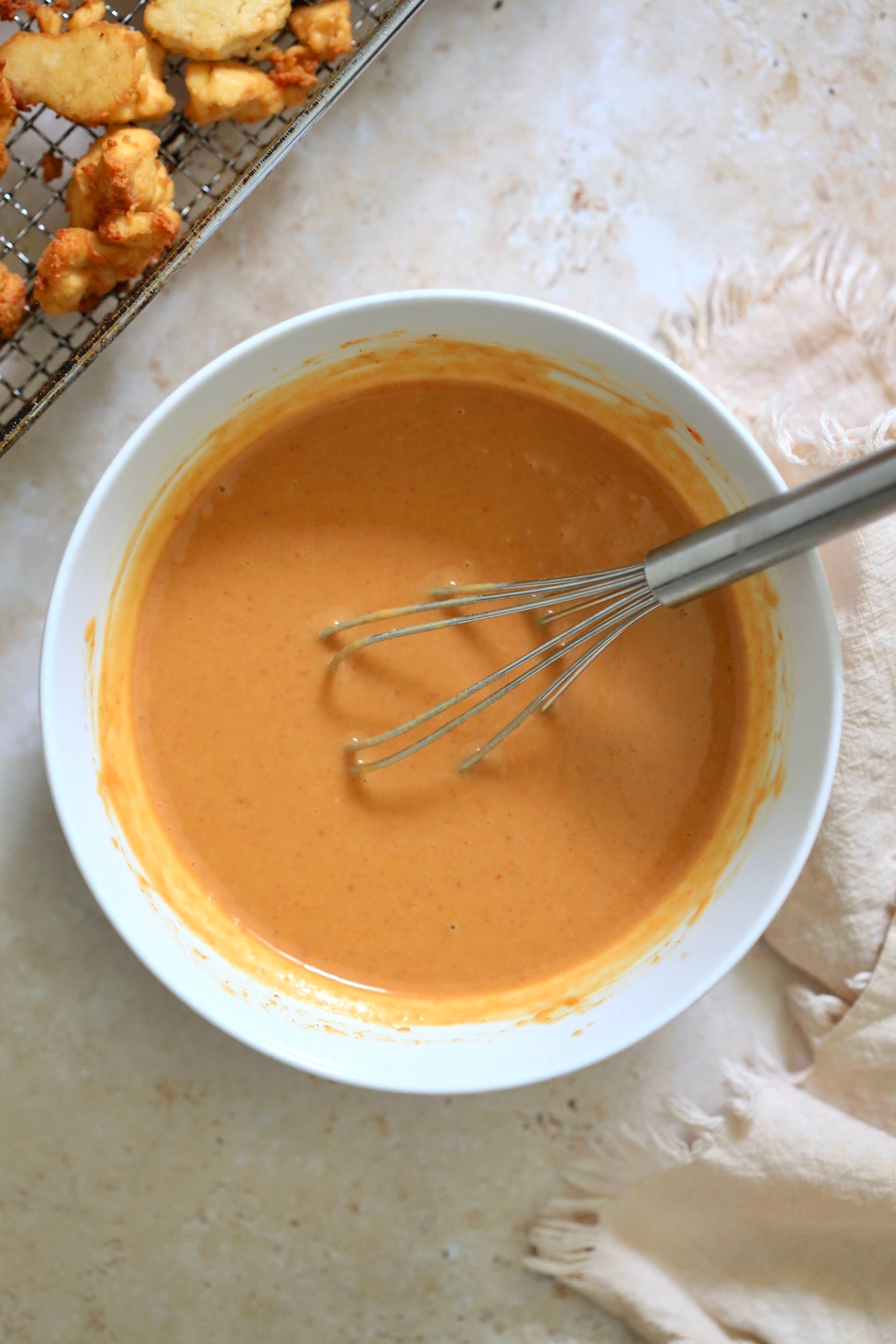orange sauce in bowl with whisk.