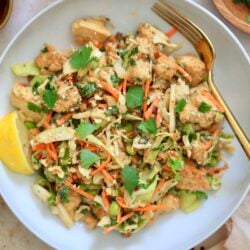 colorful cabbage salad in white bowl with gold fork.