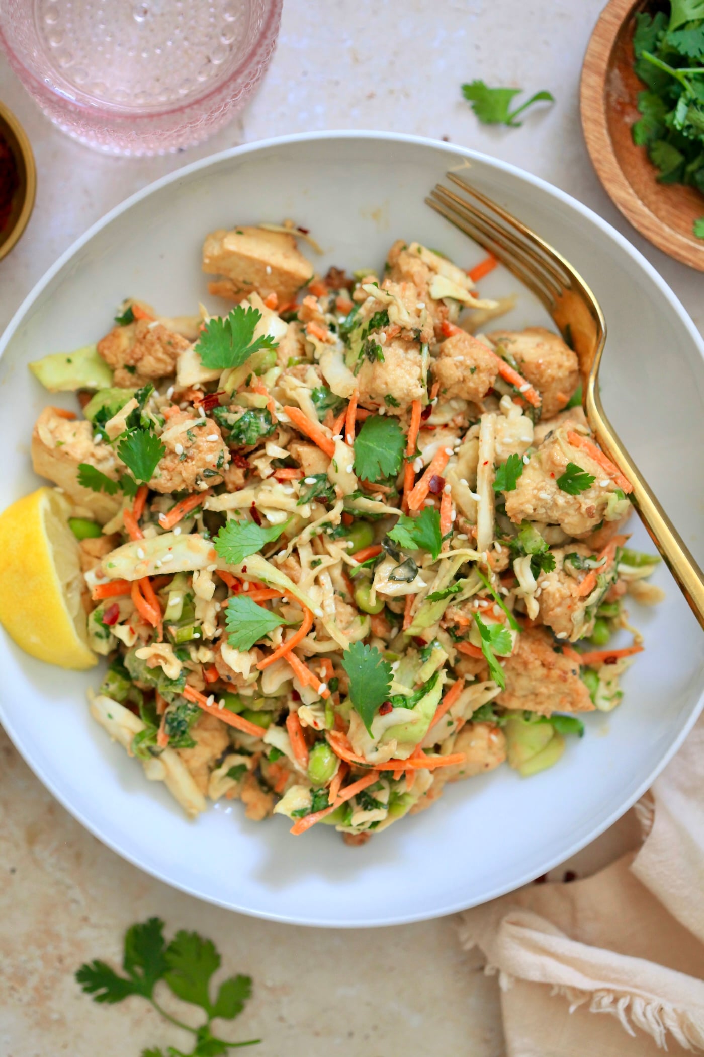 colorful cabbage salad in white bowl with gold fork.