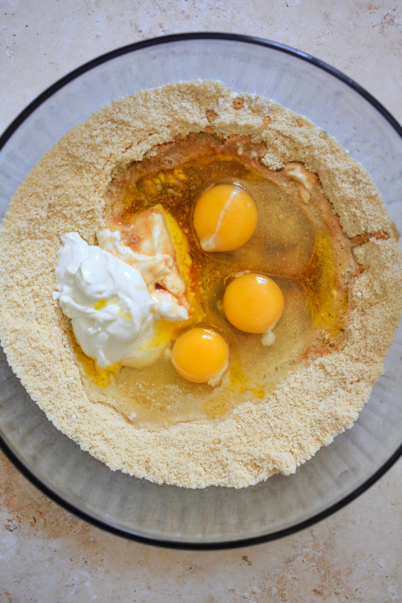 eggs and yogurt on top of flour in mixing bowl.