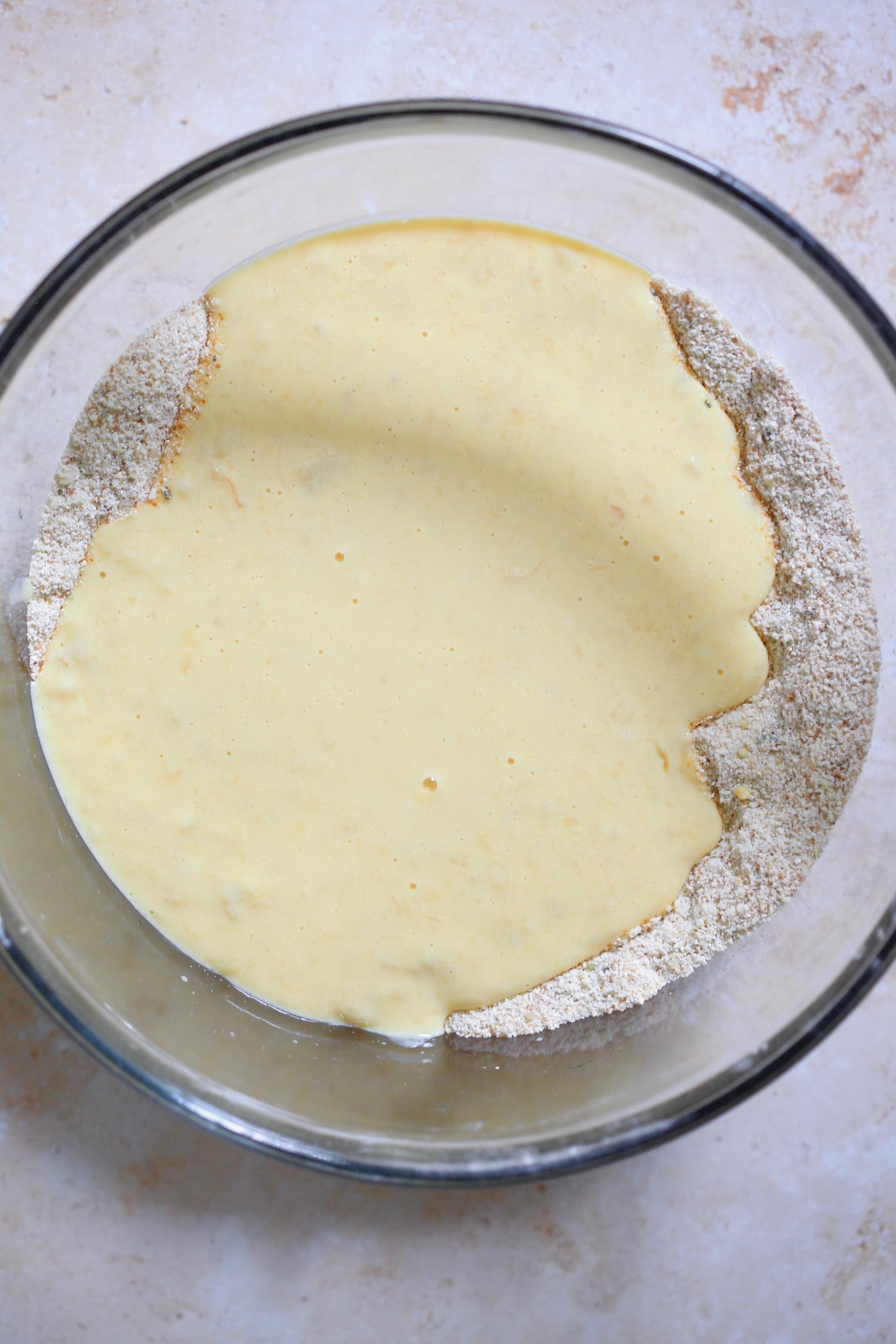 yellow wet mixture on top of flour in bowl.